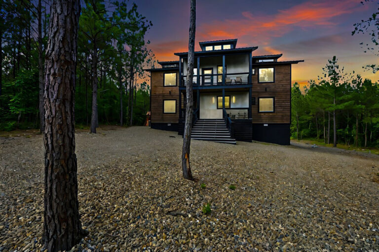 Aquarius cabin front view at sunset, with soft lighting glowing through the windows and warm tones reflecting off the wood exterior.