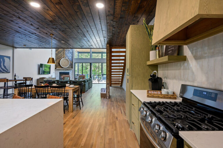 Kitchen view looking out over the dining table and living room, with large windows and open-concept design.