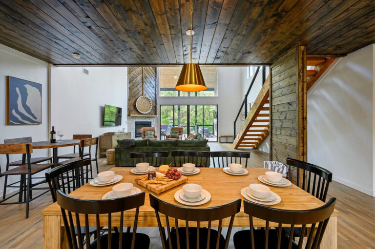 Spacious dining table with elegant place settings, with the cozy living room and fireplace visible in the background.