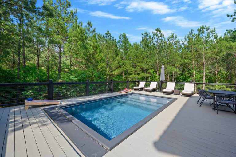 Outdoor pool surrounded by a wooded landscape and luxury lounging area at the Aquarius cabin.
