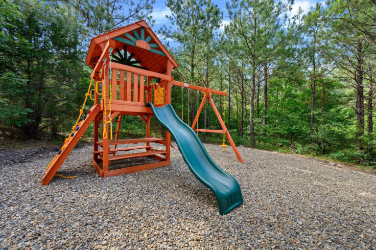 Wooden outdoor playset with slide, swings, and climbing features at the Aquarius cabin.