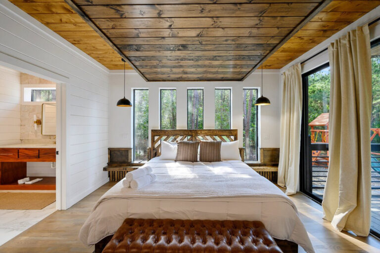 Bright bedroom with large picture windows and a neatly made bed with crisp white bedding and soft, natural accents.