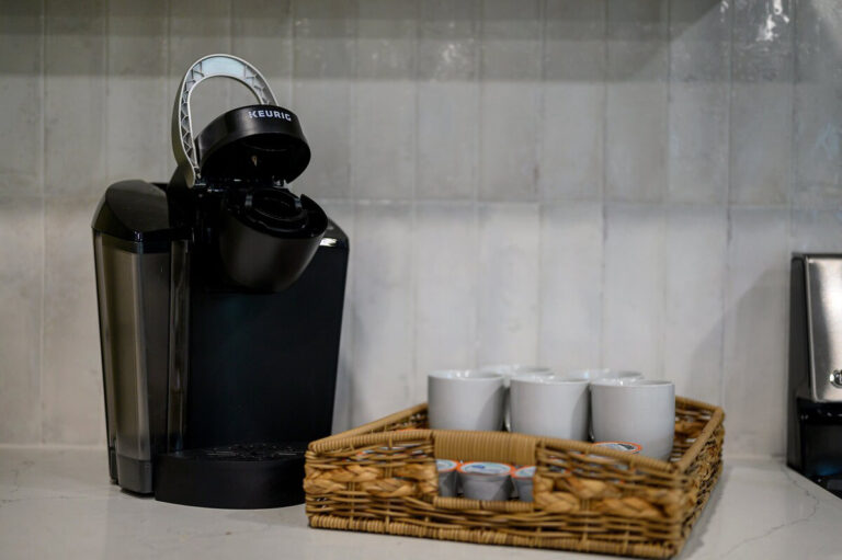 Close-up of a Keurig coffee maker with coffee pods and mugs arranged on the kitchen counter.
