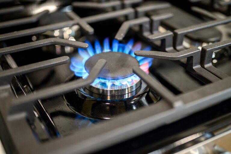 Close-up of a stainless steel gas stovetop with four burners and heavy-duty grates.