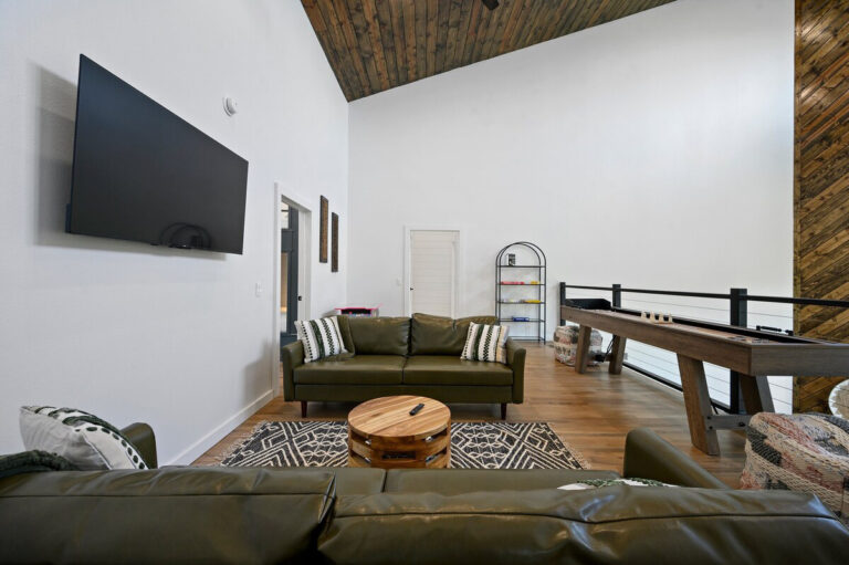 Upstairs loft area featuring modern couches, a shuffleboard table, and wood-accented walls in the Aquarius cabin.