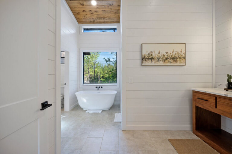 Soaking tub from above showing sleek black faucet and clean tub edges beneath a large window.