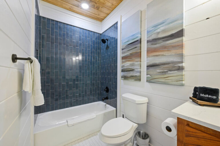 Bathroom featuring dark blue tile flooring and walls, complemented by crisp white walls and minimalist design.