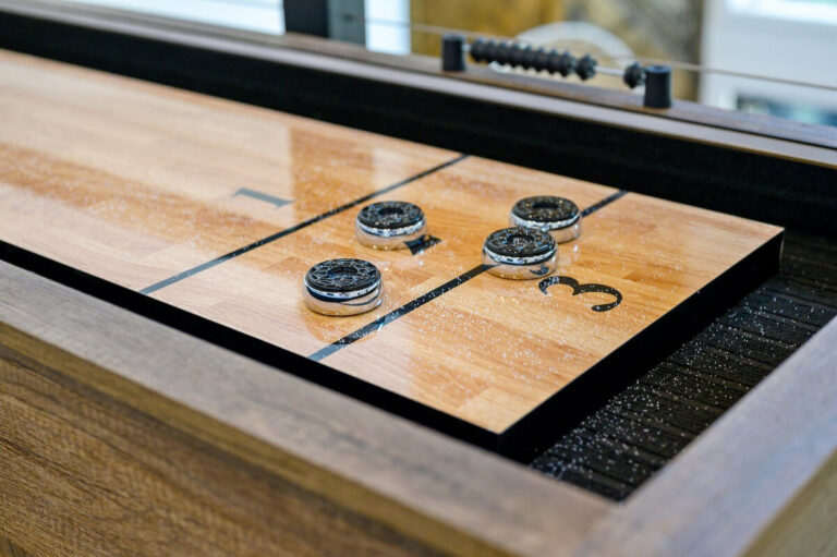 Close-up of a wooden shuffleboard table with pucks arranged on the smooth playing surface.