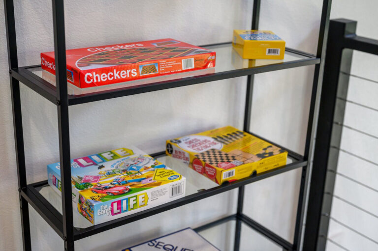 Shelf neatly stocked with a variety of family-friendly board games in the Aquarius cabin’s game area.