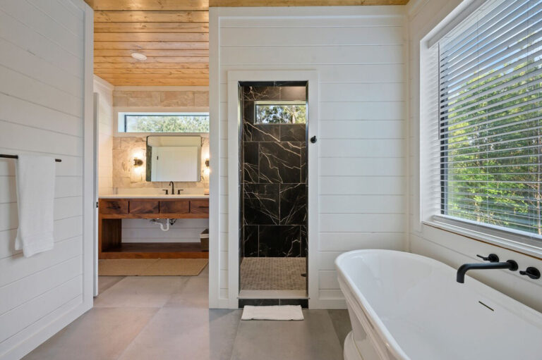 Bathroom featuring a spacious bathtub in the foreground with the sink and vanity visible past it.