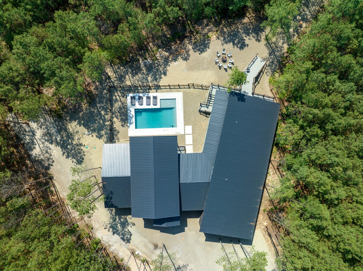 Aerial view of a luxury cabin with a private pool and fire pit, perfect for a corporate retreat in a serene forest setting.