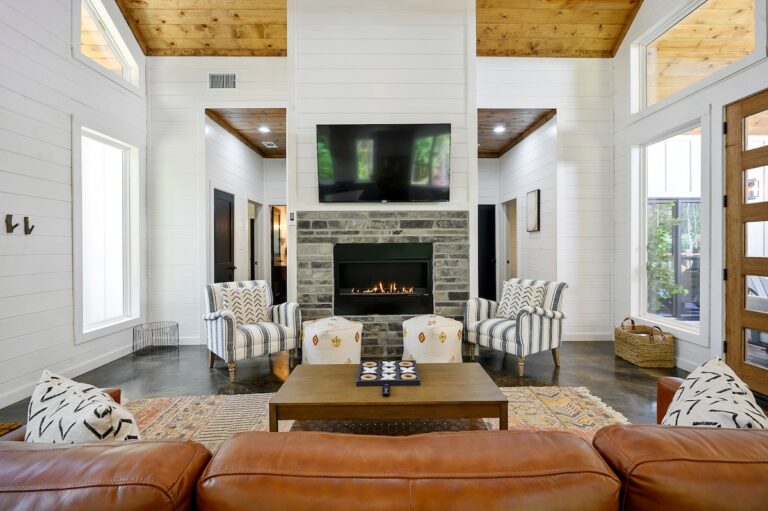 Interior view of the splish splash cabin’s living room, featuring an open floor plan with a cozy fireplace, modern furnishings, and large windows that let in natural light.