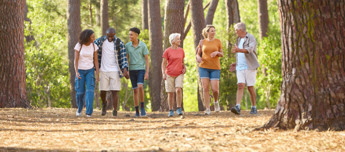 A large multi-generational family hikes together through a forest trail in Broken Bow, Oklahoma, enjoying nature and quality time during their vacation.