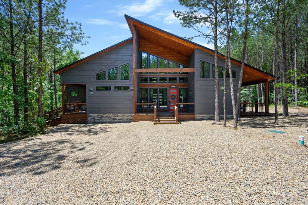 Front view of the midnight swim cabin nestled in nature, featuring a welcoming porch, cozy outdoor seating, and rustic charm.