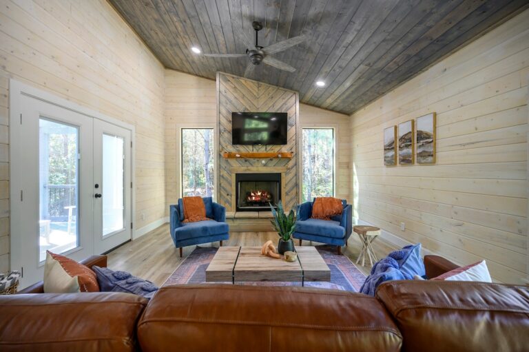 Elegant living room with fireplace, armchairs, and forest views, ideal for a couple's getaway