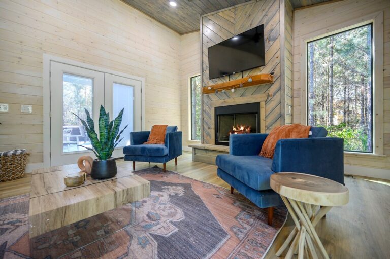 Stylish living room with fireplace, blue chairs, and large windows, ideal for a couple's getaway