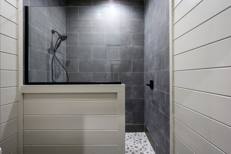 Modern shower with gray tile walls and glass partition