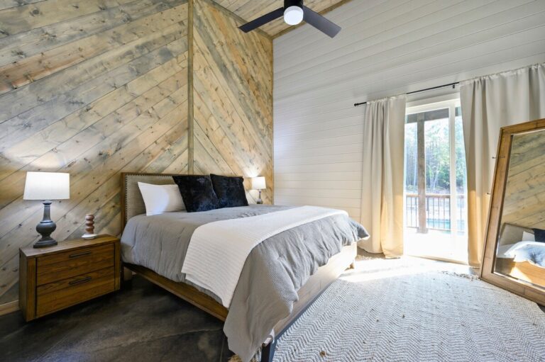 Wood accent wall bedroom with gray bedding and glass doors