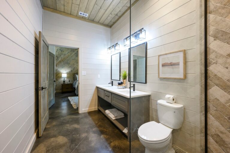 Bathroom with double vanity, mirrors, and view into bedroom