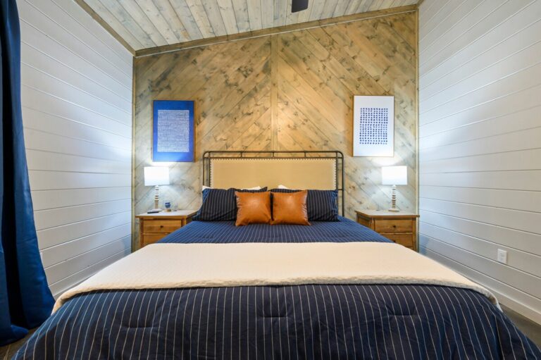 Bedroom with navy pinstripe bedding and wood accent wall
