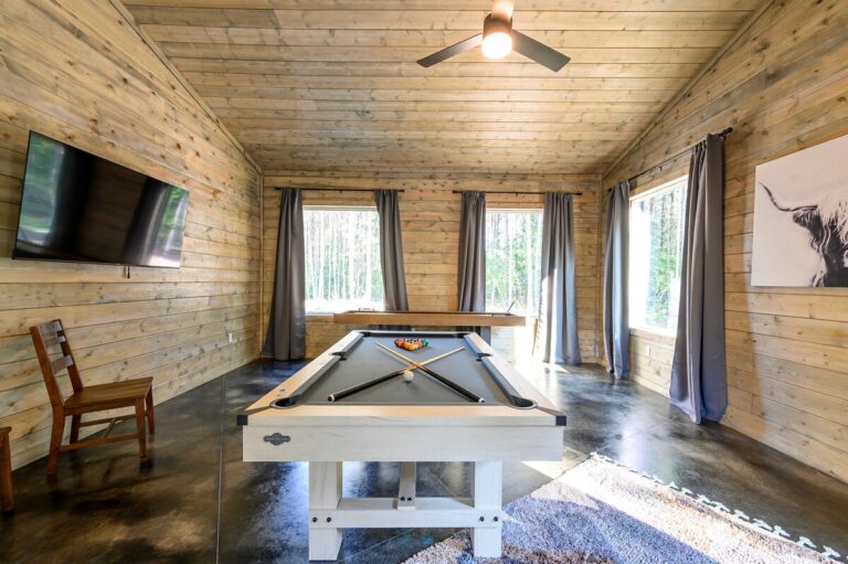 Rustic game room with pool table, shuffleboard, and large windows — family reunion activities