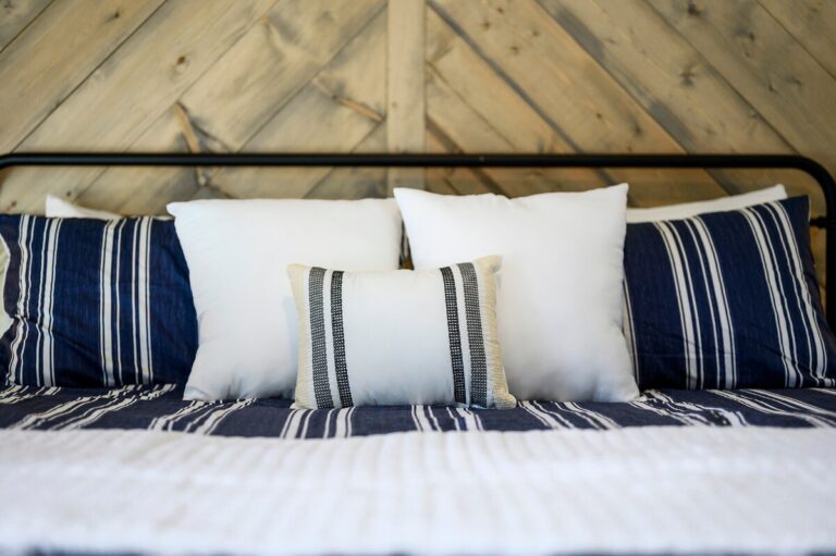 Close-up of striped bedding and throw pillows on cozy bed — family reunion lodging