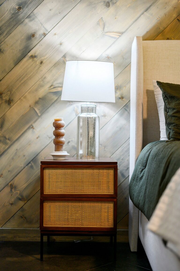 Modern nightstand with wicker drawers and table lamp beside bed — family reunion rental