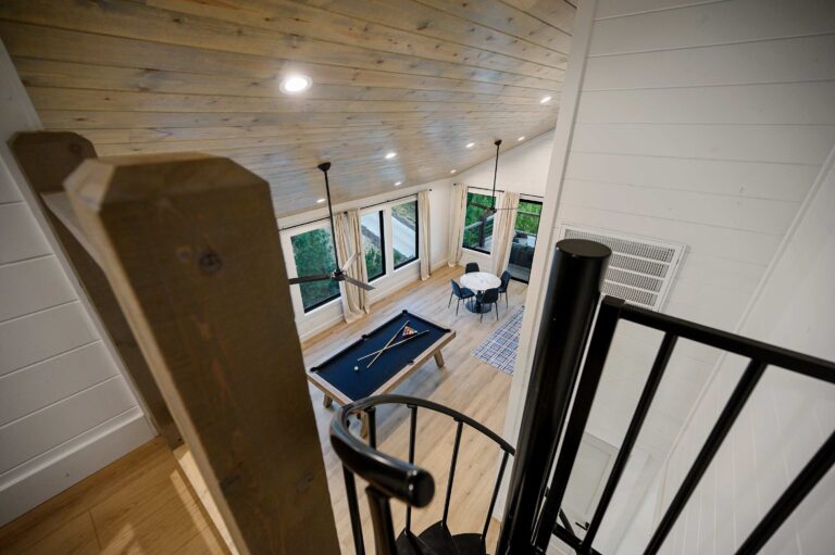 Game room with pool table and spiral staircase in large family vacation lodge