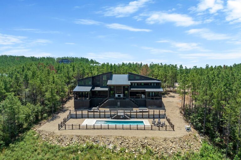 Aerial view of luxury cabin with private pool surrounded by pine forest, perfect for stargazing retreats.