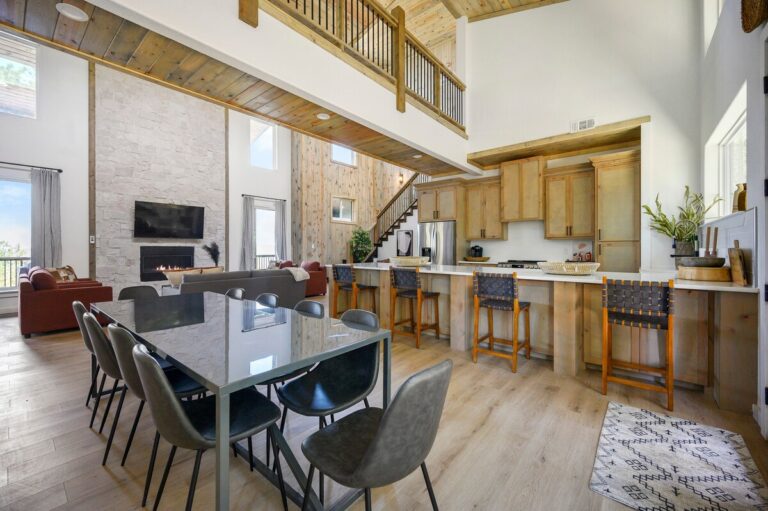 Dining table and chairs in Sky Dive pet friendly cabin, set beside a stone fireplace and perfect for group meals before stargazing at the outdoor fire pit.
