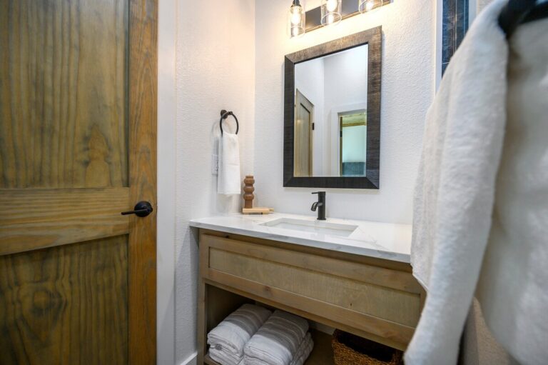 Bathroom vanity with mirror and rustic wood design at Sky Dive cabin, providing convenience for stargazing getaways.