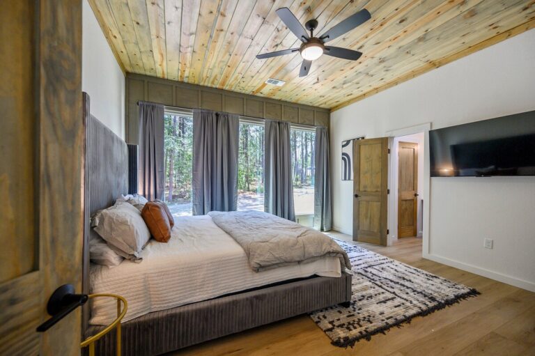 Bedroom with large windows and forest views at Sky Dive cabin, offering peaceful mornings after stargazing nights.