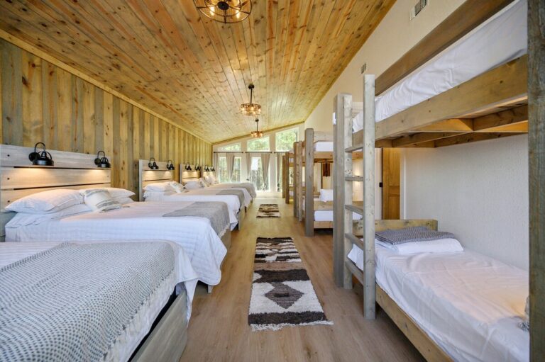 Spacious bunk room at Sky Dive cabin with multiple beds for groups, designed for family gatherings and stargazing retreats.