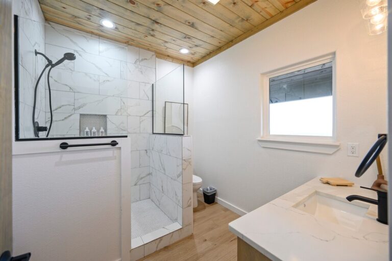 Modern marble tile bathroom with walk-in shower at Sky Dive cabin, offering comfort for guests enjoying stargazing retreats.