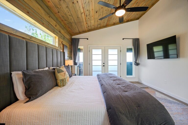 Bedroom with gray headboard and TV for stargazing stays at Sky Dive Cabin