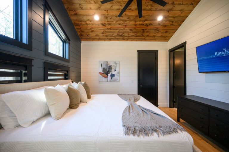 King bed and rustic modern décor inside Blue Note Broken Bow cabin with cozy retreat atmosphere near river activities and outdoor fire pit.