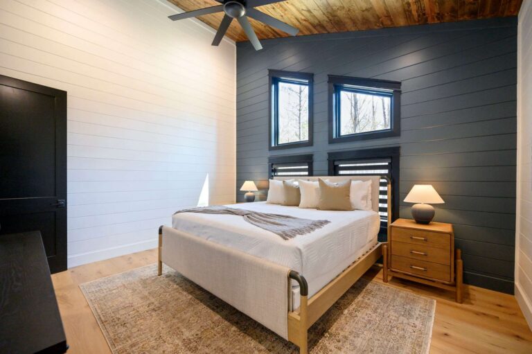 Elegant king bedroom inside Blue Note Broken Bow cabin with dark accent wall and cozy modern cabin design near river activities.