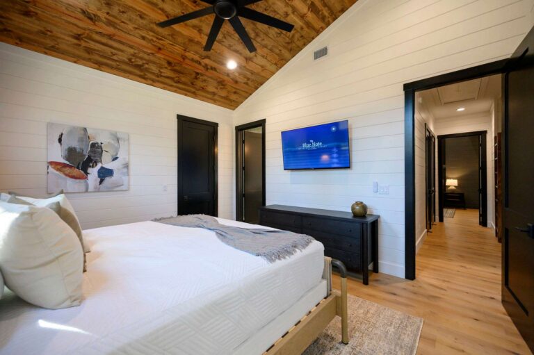 Spacious king bedroom inside Blue Note Broken Bow cabin with wood ceiling accents and modern design near outdoor fire pit and river activities.