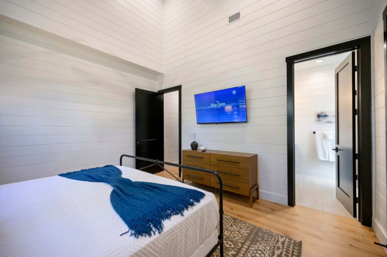 Spacious primary bedroom suite at Blue Note Broken Bow cabin with vaulted ceilings and modern rustic décor near outdoor fire pit.