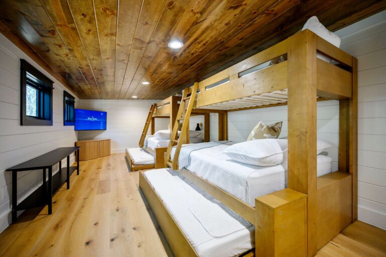 Rustic bunk room at Blue Note Broken Bow cabin with custom bunk beds, trundle beds, and entertainment area near outdoor fire pit.
