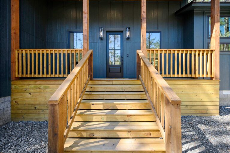 Front entrance of Blue Note Broken Bow cabin surrounded by trees near outdoor fire pit and river activities.