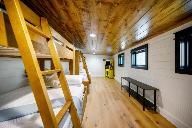 Spacious bunk room inside Blue Note Broken Bow cabin with multiple built-in bunks and arcade game near river activities and outdoor fire pit.