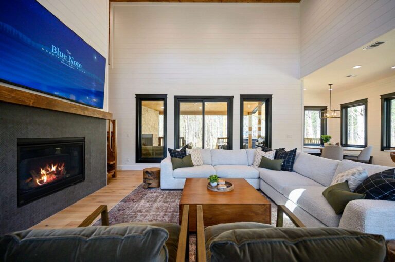 Open living area inside Blue Note Broken Bow cabin with fireplace and patio access near outdoor fire pit.