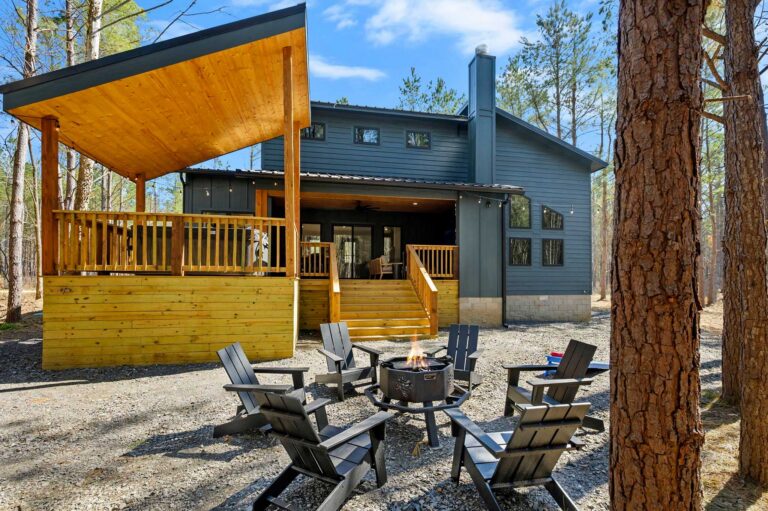 Exterior view of Blue Note Broken Bow cabin with covered deck, outdoor fire pit seating, and luxury wooded retreat near river activities.