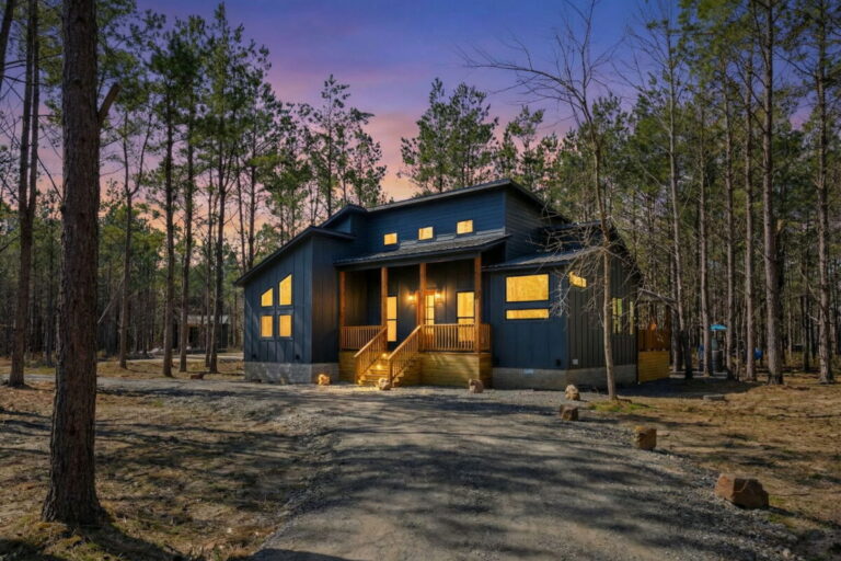 Blue note broken bow cabin exterior at sunset surrounded by forest near outdoor fire pit and river activities.